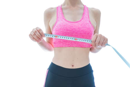 Young woman measuring her waist with a tape measure isolated on white backgroundの写真素材