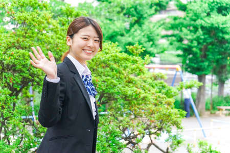 Student waving her hands with smileの写真素材
