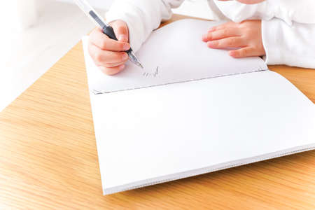 Close-up image of a child's hand writing in a notebookの写真素材