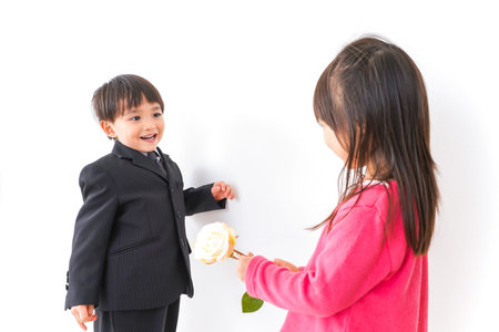 Child giving a flower to his mother in front of a white wall