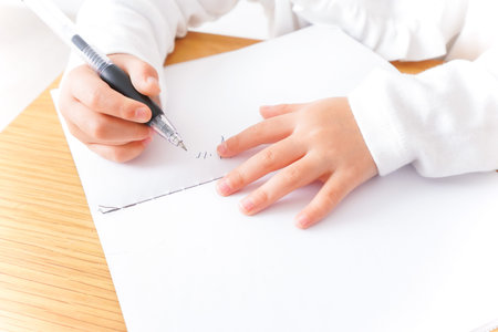 Child drawing with a felt-tip pen on a sheet of paper