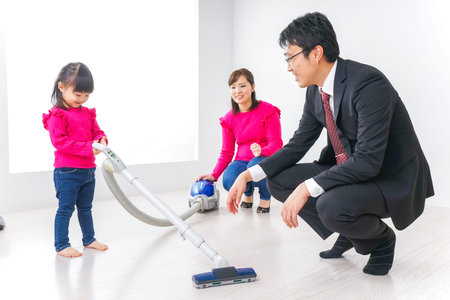 Asian family vacuuming the living room at home. Happy family concept.