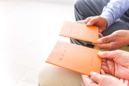 Close up of senior asian man and woman hands holding red envelopes.の写真素材