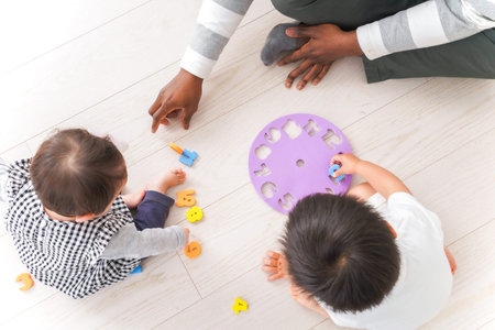 Top view of boy and girl playing with wooden toys on floor at homeの写真素材