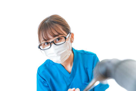 Young female dentist in a blue uniform and mask on a white backgroundの写真素材