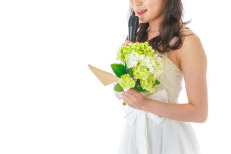 Beautiful bride in wedding dress holding a bouquet of flowers and a microphoneの写真素材