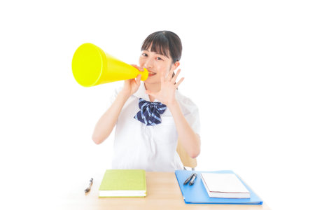 A teenage girl holding a megaphone shot in the studio, isolated on white