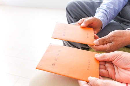 Close-up Of Senior Couple's Hand Holding Envelopeの写真素材