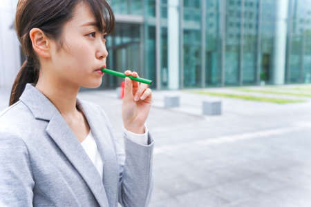 Businesswoman holding a green pen in the city high-rise buildingsの写真素材