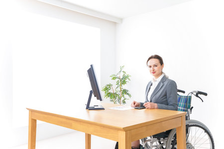 Disabled businesswoman working at the office with a wheelchair in the foreground