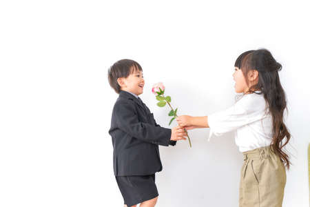 Child and teacher giving a flower shot in the studio on a white backgroundの写真素材