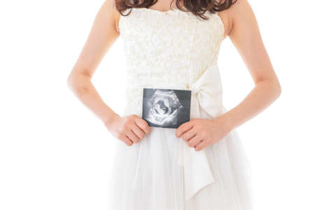 A pregnant woman holding an ultrasound image of her baby in her handsの写真素材