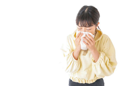 Young woman sneezing in a handkerchief high quality photoの写真素材