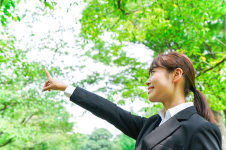 Business woman pointing with green backgroundの写真素材