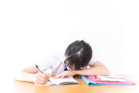 Teenage girl studying at desk shot in the studio on white backgroundの写真素材