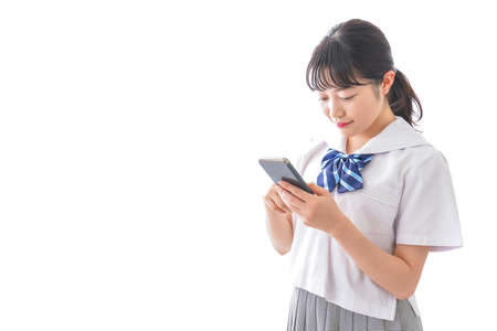 A high school girl using a smartphone shot in the studio on white backgroundの写真素材