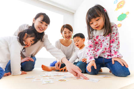 Children and teacher playing board game in the living room high quality photoの写真素材