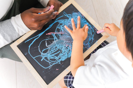 Top view of a child drawing with chalk on a blackboard.の写真素材