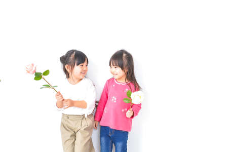 Childhood, family, happiness and happiness concept - happy asian little girls with flower over white backgroundの写真素材