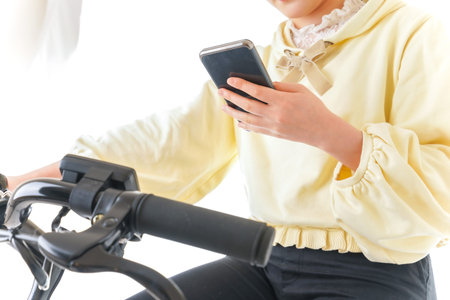 Young woman riding bicycle and using smart phone, closeup of hands