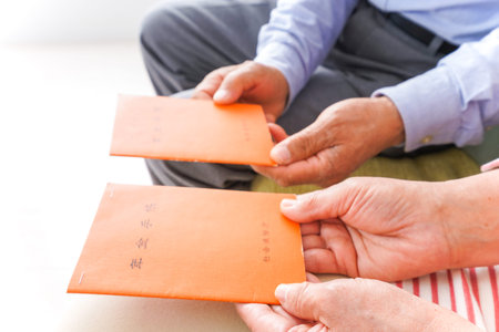 Close-up of senior couple's hands holding red envelopes.