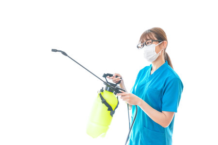 Nurse wearing mask and holding disinfectant sprayer on white backgroundの写真素材