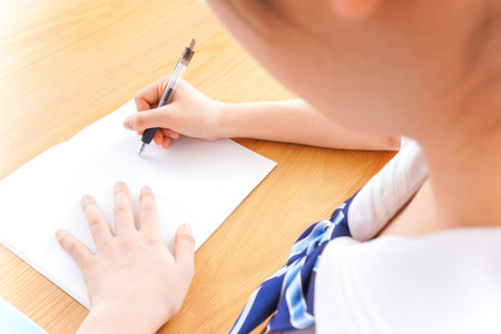 Boy writing in notebook at home, closeup. Early education concept