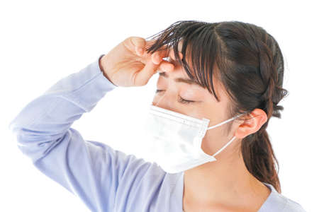 Young woman with a medical mask on her face, isolated on white backgroundの写真素材