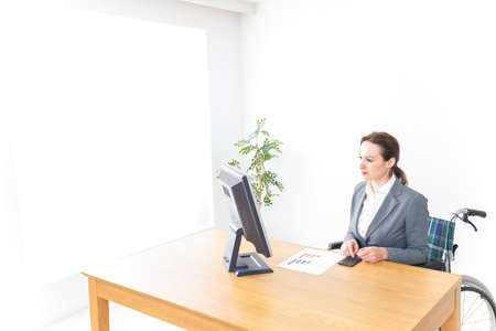 Woman in wheelchair working at the office image with copy spaceの写真素材