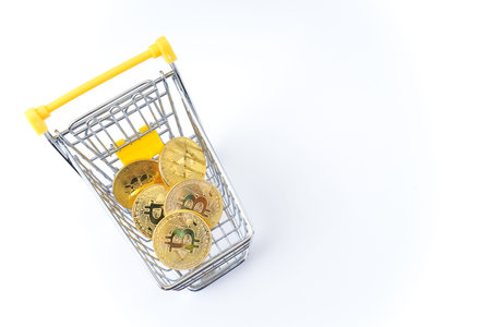 Shopping cart with golden bitcoins on white background. Cryptocurrency concept.