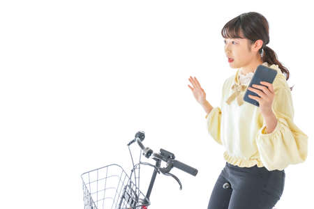 Young woman riding a bike and using a smart phone shot in the studioの写真素材