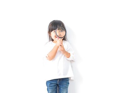 Little girl looking through a magnifying glass on a white background.