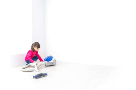 Child cleaning the white room with a vacuum cleaner, high quality photoの写真素材