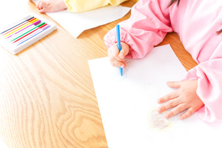 Little girl drawing with colorful pencils on wooden table, closeup