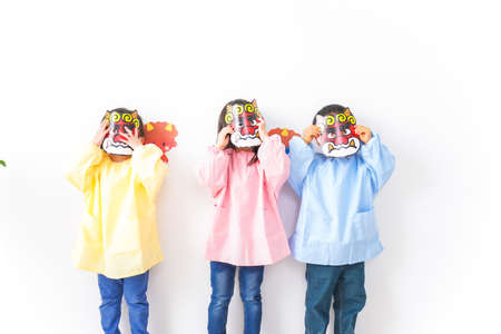 Children playing with theater masks in front of a white wall shot in the studioの写真素材