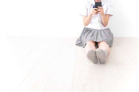 Young woman sitting on the floor and using smart phone, stock photoの写真素材
