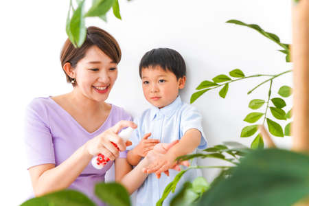 A young mother and her son taking care of the plants at homeの写真素材