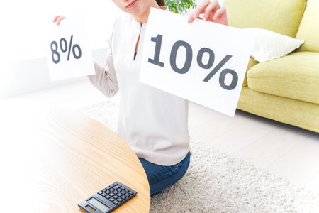 Woman holding a paper with the word 100 percent and a calculator in the living room