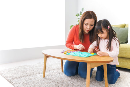 Mother and daughter playing board game at home. Happy family concept.