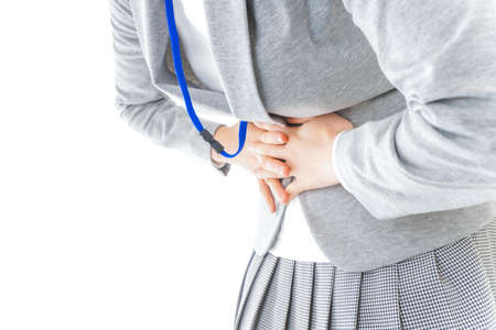 Woman suffering from backache and holding a stethoscope on white backgroundの写真素材