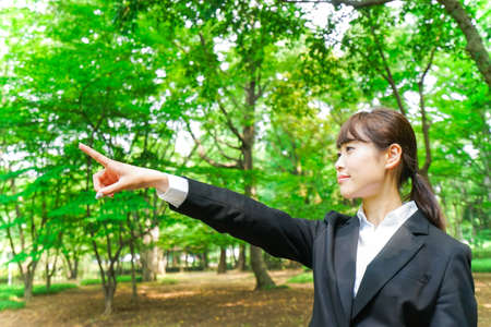 Business woman pointing with green backgroundの写真素材