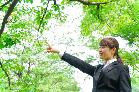 Business woman pointing with green backgroundの写真素材