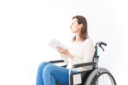 Woman reading a newspaper and sitting on a wheelchair - isolated on white