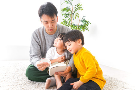 Father and children reading book together at home. Happy family concept.