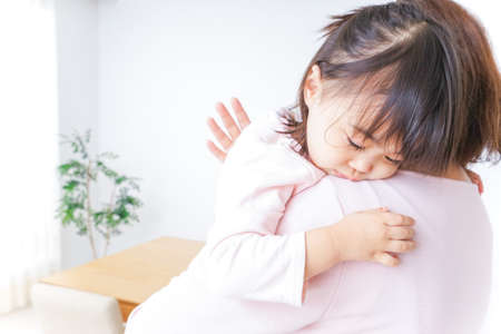 Sleeping child carried by motherの写真素材