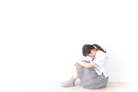 Girl sitting on the floor and holding a knee high angle viewの写真素材
