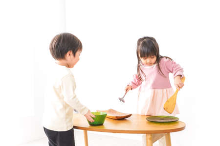 Children cooking in the dining room, shot in the studio on a white background.の写真素材