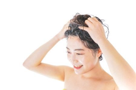 Young woman washing her hair in the shower, isolated on white background