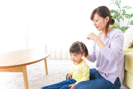 Mother tieing child's hair togetherの写真素材