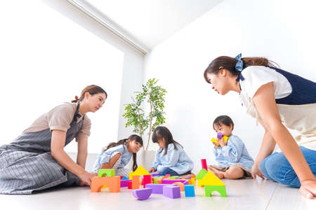 Children  and teacher playing with toyの写真素材